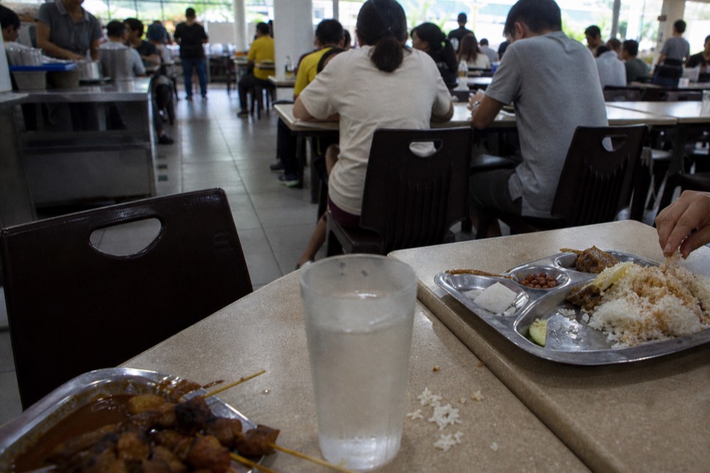 Food court tables with trays of Malaysian dishes, no text, no logos, no people
