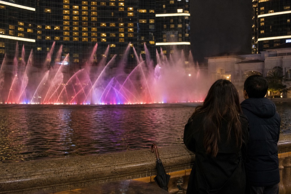 Lake Symphony fountain show spraying water in front of the illuminated Petronas Twin Towers at night, no text, no logos, no people
