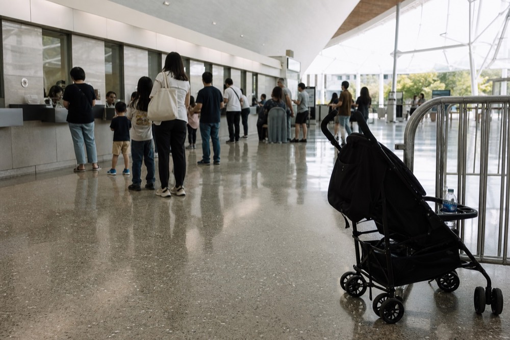 Families queuing at an aquarium ticket counter in a bright lobby, no text, no logos, no people