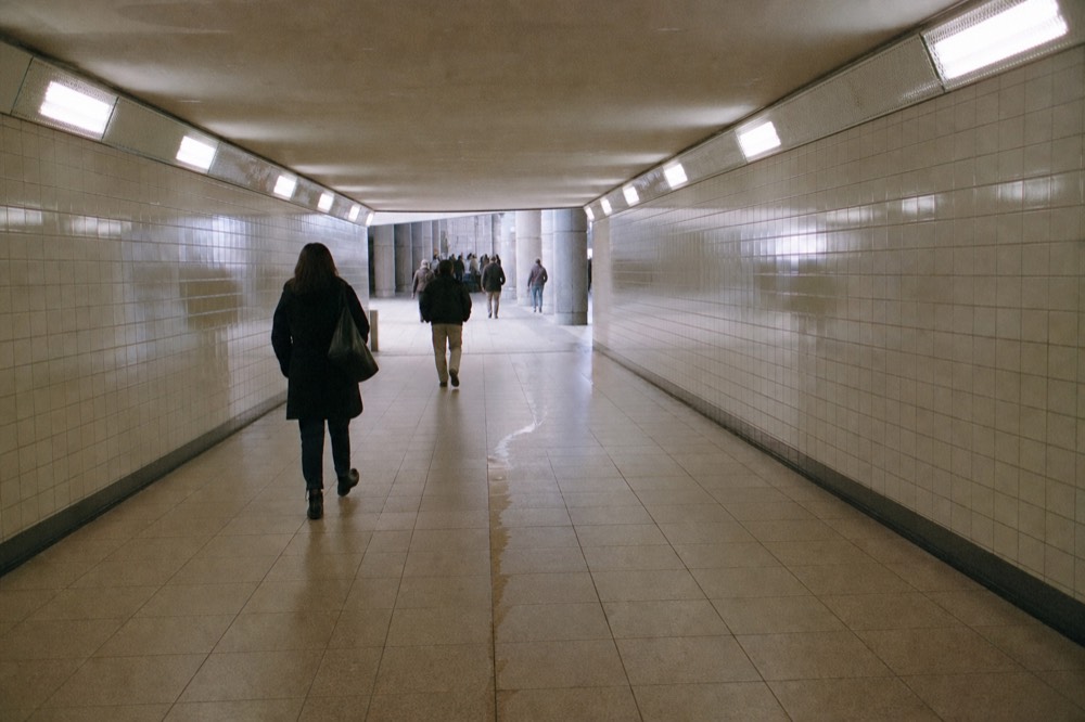 A covered walkway leading toward a convention centre entrance between glass buildings, no text, no logos, no people