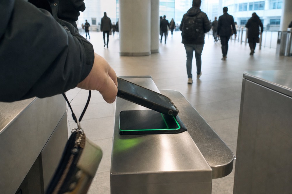 A guest scanning a phone QR code at an aquarium turnstile, no text, no logos, no people