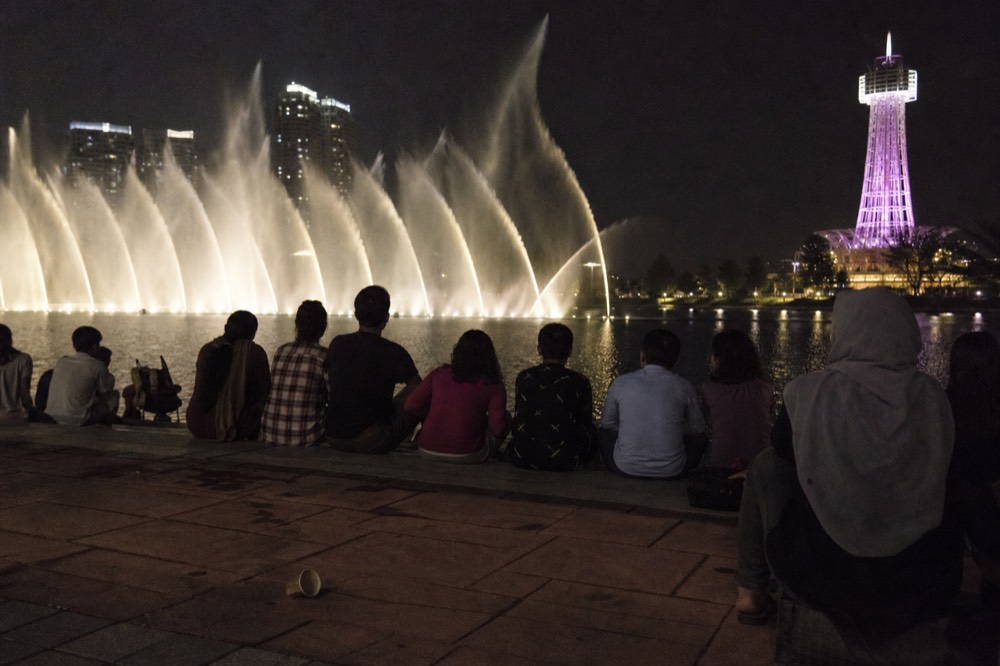 The Lake Symphony fountains spraying water in lit patterns at night with crowds at the lake edge, no text, no logos, no people