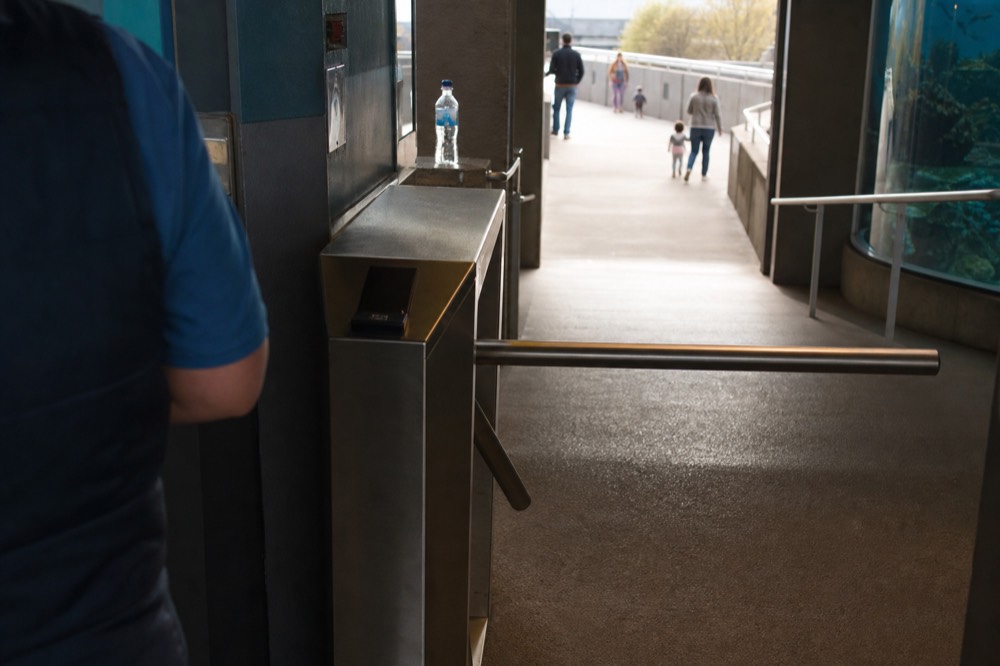 Turnstile entry at an aquarium entrance with staff assisting visitors, no text, no logos, no people