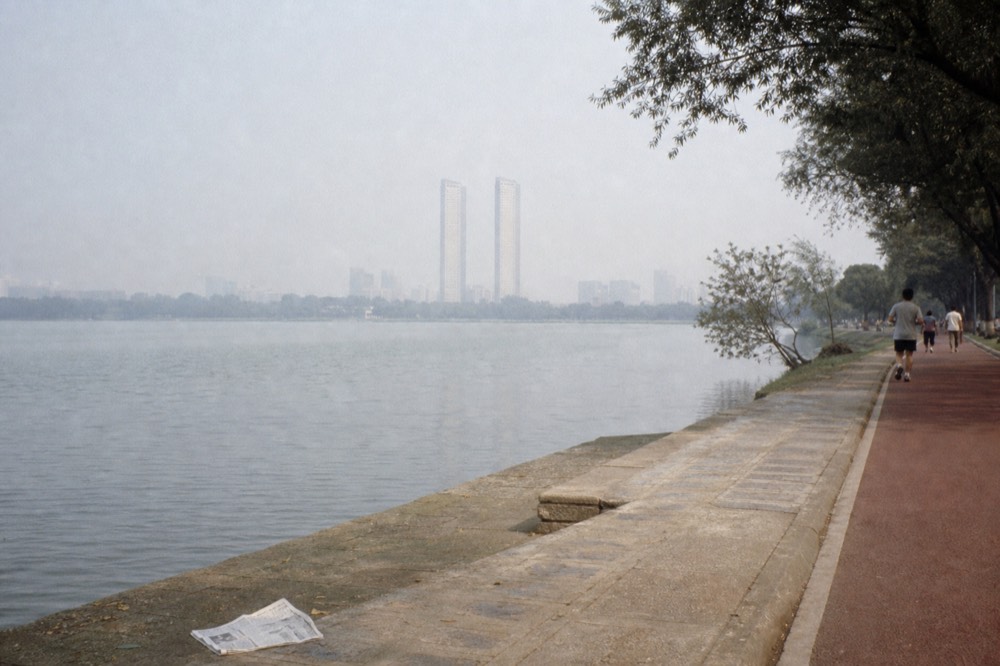 Wide view across the KLCC Park lake with the Petronas Twin Towers behind, no text, no logos, no people