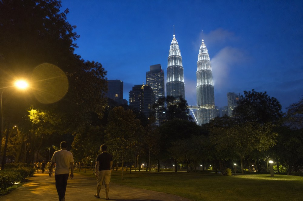 The KLCC skyline glowing after sunset with the park and towers lit up, no text, no logos, no people
