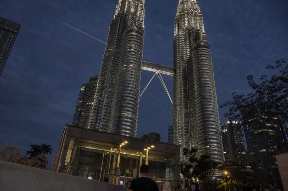 The Petronas Twin Towers illuminated against a dark evening sky, no text, no logos, no people