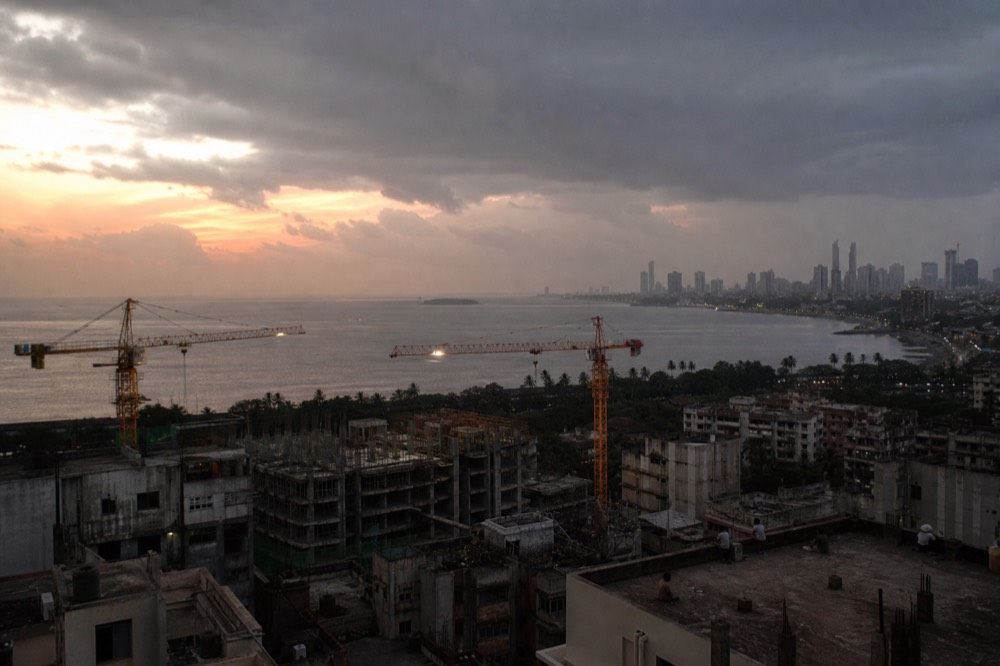 A waterfront city skyline at dusk with construction cranes, no text, no logos, no people