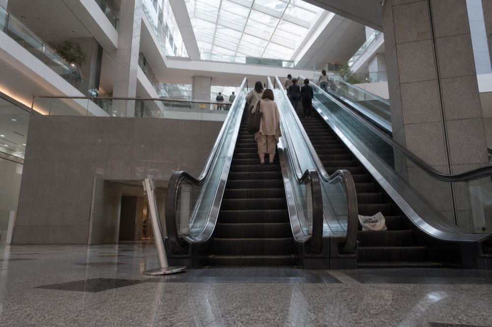 Escalators rising through a bright multi-level mall atrium, no text, no logos, no people